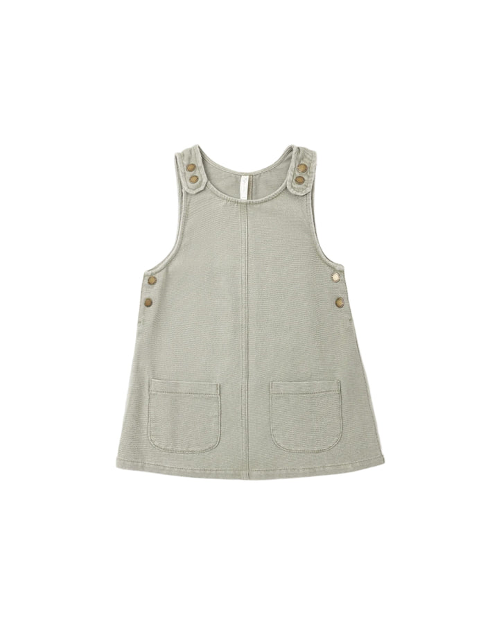 A sleeveless light sage green pinafore-style top with front pockets and decorative buttons on the shoulders and sides, shown on a plain white background.