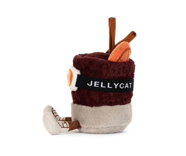 A Jellycat plush toy shaped like a mug, featuring a dark red knit top, a beige bottom, a black band with the white &