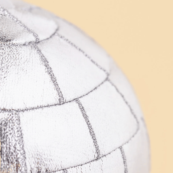 Close-up of a white textured product with stitched panel lines against a pale beige background.