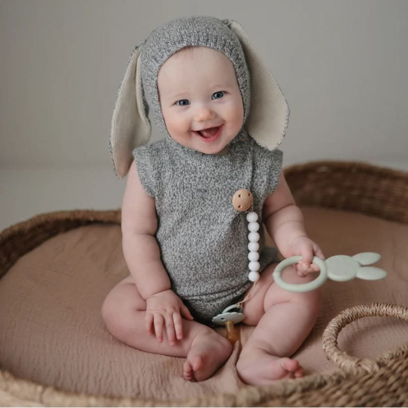 Baby wearing a gray bunny costume sitting in a woven basket.